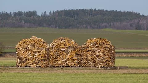 Three large round piles of stacked firewood on open field Stock Photos