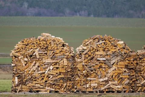 Three large round piles of stacked firewood on open field Stock Photos