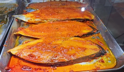 Three large, sliced fish, generously coated in vibrant red spices Video stock 312003090