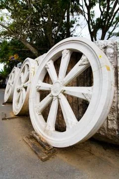 Three large wheels made of stone stand against the wall. Stock Photos