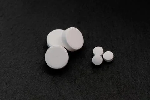 Three large white tablets and three small ones on a black background. Foto stock
