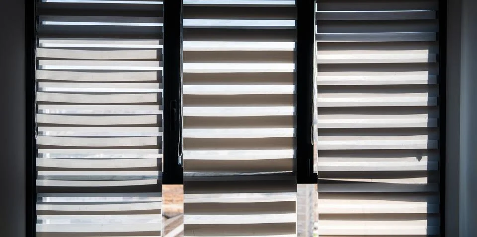 Three large windows with zebra blinds in bright interior with sunlight Foto stock