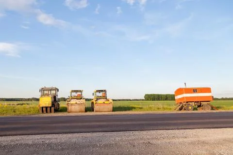 Three large yellow asphalt compactor standing on the side of the track mobile Stock Photos