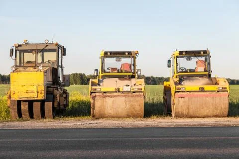 Three large yellow asphalt compactor standing on the side of the track during Stock Photos