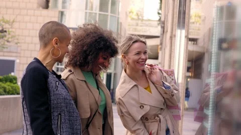 Three laughing middle aged cheerful women looking at shopping window display Stock Footage 249905467