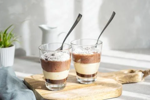 Three-layer chocolate and vanilla mousse dessert in glass cups, sprinkled with Stock Photos