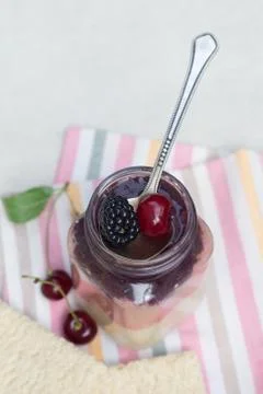 Three-layer smoothie of cherry and blackberry in a glass jar Stock Photos