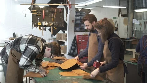 Three leather professionals assembling bags in studio. Video stock 94535824