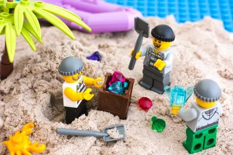 Three Lego robbers digging out box of gems from sand on the island Stockfoto's