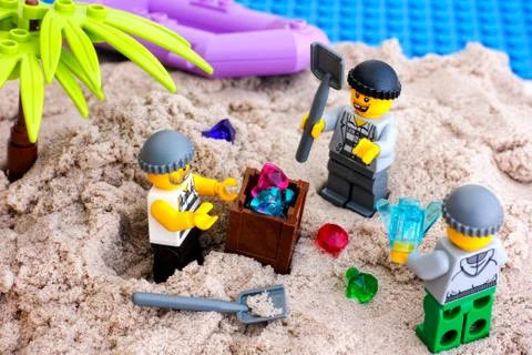 Three Lego robbers digging out box of gems on island 库存照片