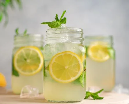 Three Lemon mojito cocktail with mint in mason jars on top of wood. lemon moj Stock Photos