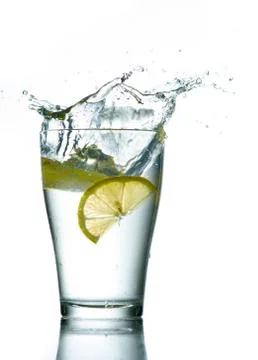 Three lemons are falling into the glass of water. Stock Photos