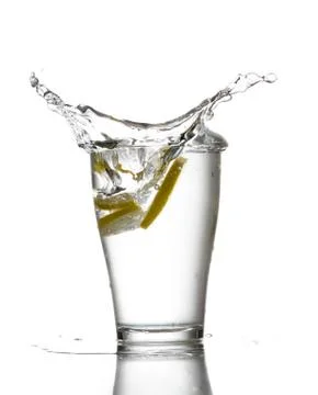 Three lemons are falling into the glass of water. Stock Photos