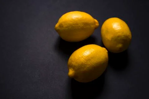 Three lemons on the black surface Stock Photos