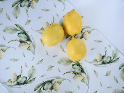 Three lemons on a bright printed tablecloth Stock Photos