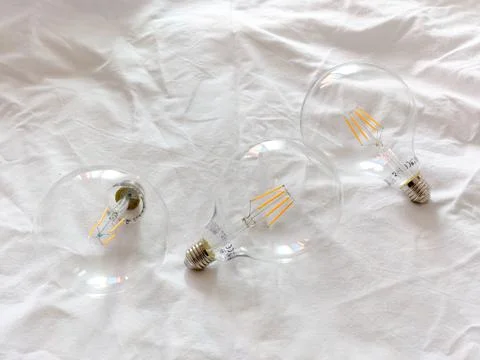 Three light bulbs on a white surface Stock Photos
