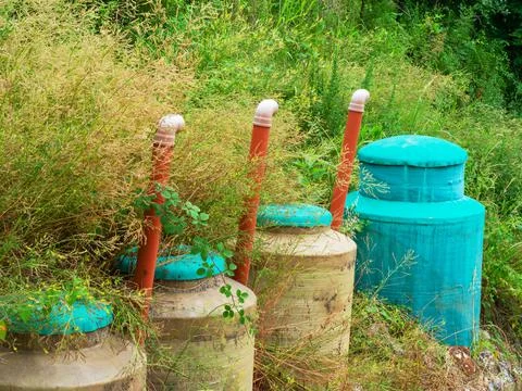 Three light-colored cisterns with blue lids and one completely blue with orange Stock Photos