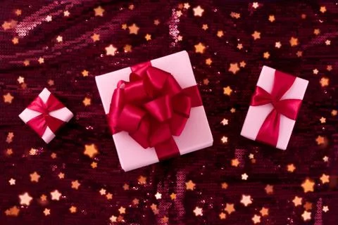 Three light pastel pink boxes tied with a red satin ribbon. Stock Photos