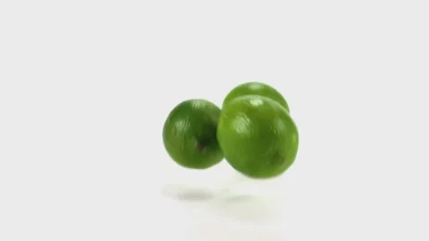 Three limes tumble and fall in slow motion onto a white cyc Stock Footage 70681004