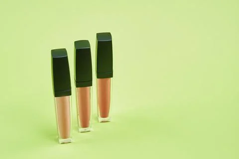 Three lipsticks of different colors pattern on a green background isolated Foto stock