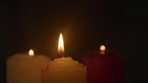 Three Lit Candles Glowing Warmly Against Dark Background Vidéo 335498234