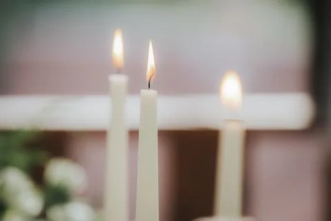 Three lit white candles with soft flames on a blurred background, surrounde.. Stock Photos