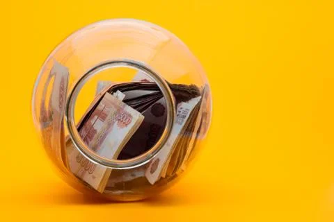 In a three-liter jar are five thousandth notes, the jar lies on its side with Stock Photos