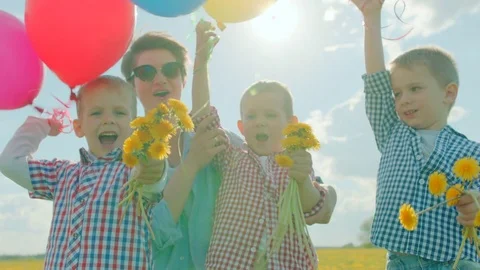 Three little boys and their mom smiling with colour balloons and flowers Stock Footage 79217441