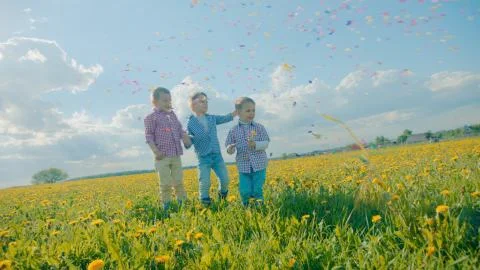 Three little boys exploding party cracker and catching confetti Stock Photos