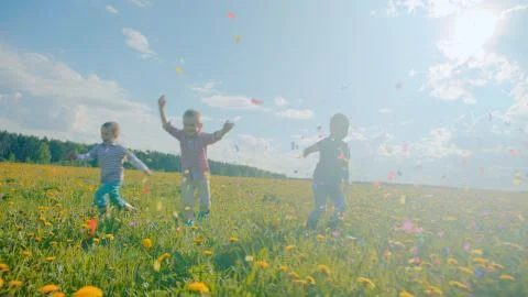 Three little boys exploding party cracker and catching confetti Stock Photos