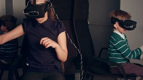 Three little kids in vr headsets enjoying virtual reality game Stock Footage