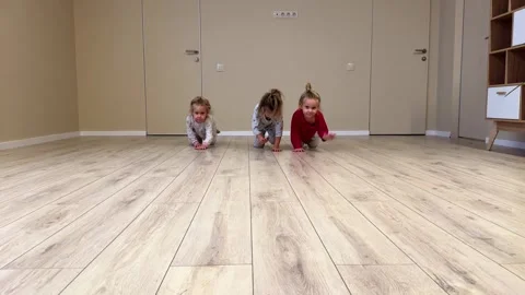 Three little sisters triplets crawl around the room at home in pajamas with bare Video stock 257254498