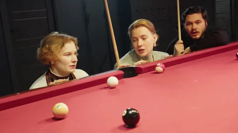 Three lively caucasian friends coordinate their next move over billiards table Stock Footage 329193045