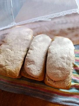 Three loaves of bread sitting on top of a colorful towel Stock Photos