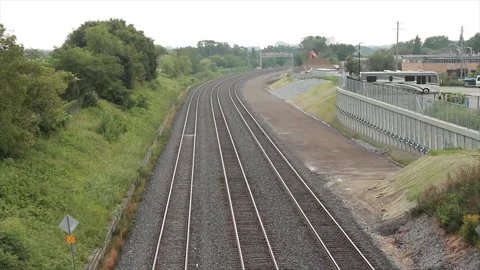 Three long railroad tracks with bend curve next to grass trees and dirt with sky Stock Footage 249417894