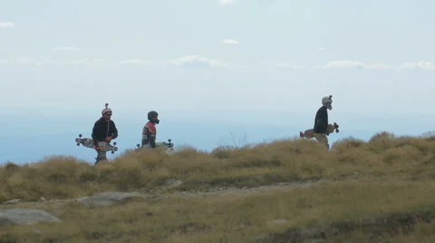 Three longboarders walking and a yellow car passing by on Transalpina Stock Footage 57786152