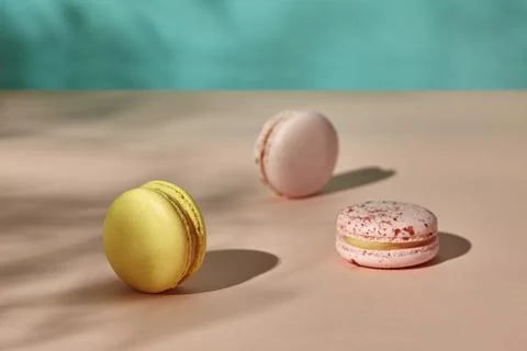 Three macarons on light pink and pale blue background Stock Photos