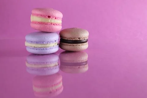Three macaroons of different color lavender coffee chocolate pink on a pink b Stock Photos