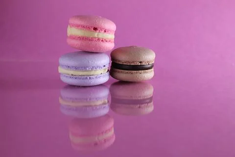 Three macaroons of different color lavender coffee chocolate pink on a pink b Stock Photos