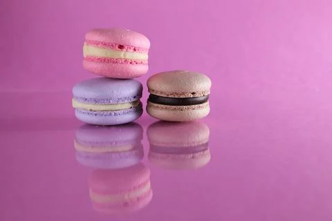 Three macaroons of different color lavender coffee chocolate pink on a pink b Stock Photos