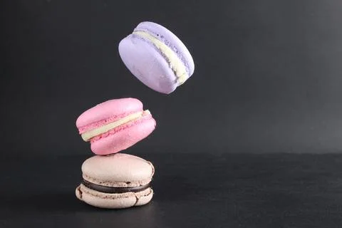 Three macaroons fall flying levitating food against a black background. After Stock Photos