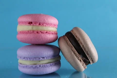 Three macaroons lie triangle on a blue background with a place for text and c Stock Photos