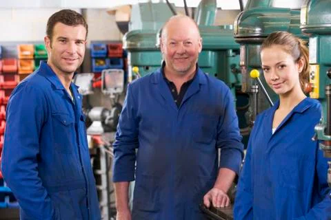 Three machinists in workspace by machine talking Stock Photos