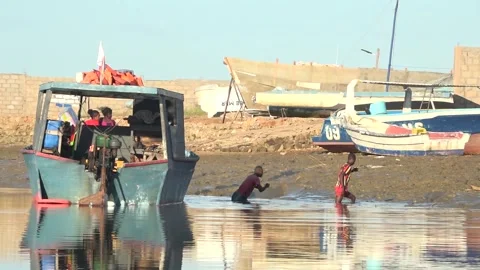 Three Malagasy men busy with loading a motorboat in local fishing village Stock Footage 313563443
