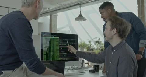 Three Male Engineers looking at Code on Computer Monitor in Office Stock Footage 240228437