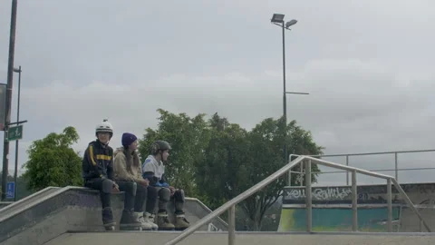 Three males jump and rail at skatepark while three other people watch them Stock Footage 171491010