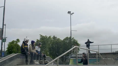 Three males jump at skatepark while three people watch and clap at them Stock Footage 171493010