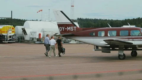 Three Man Crew Walk Around Rear of Plane to Board Twin Engine Turboprop Stock Footage 99376180
