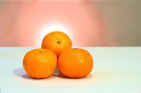 Three mandarins on a blue table. Stock Photos