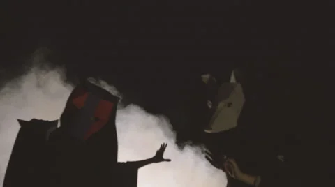 Three masked people hexing by the fire - then suddenly turning their heads Stock Footage 59360052